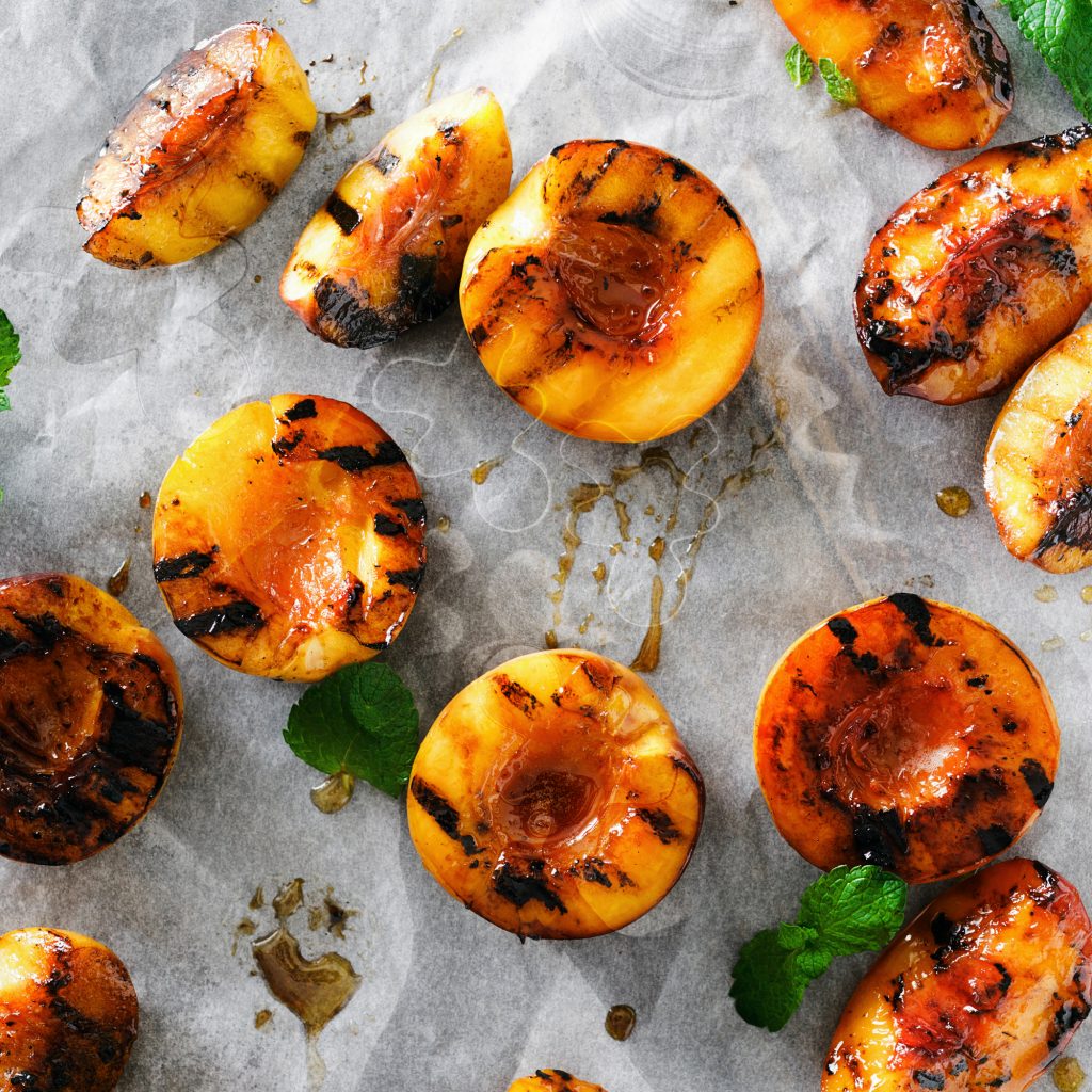 Top view grilled peaches served with mint leaves on paper. Copy space